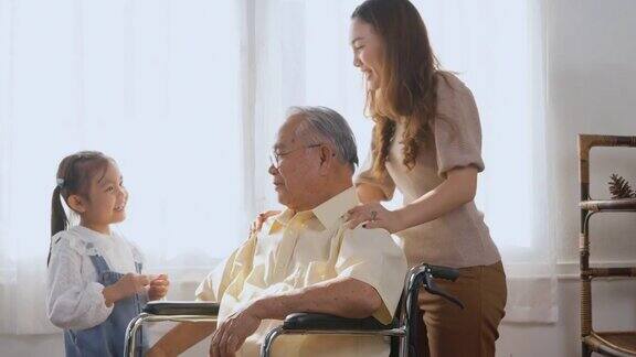 残疾老人坐在轮椅上女儿和孙女微笑着一起在客厅里玩耍