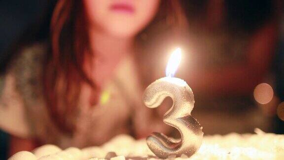 孩子吹蜡烛在生日蛋糕庆祝三岁