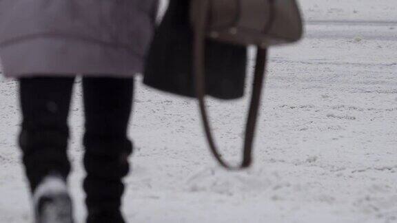 在冬日暴风雪期间行人在红绿灯前过马路腿特写天气恶劣的道路交通