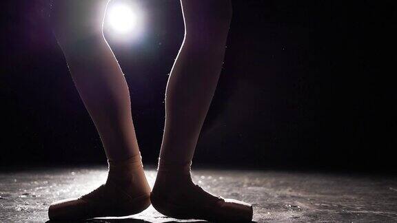 漂亮的腿在黑色的背景尖头鞋芭蕾舞练习缓慢的运动