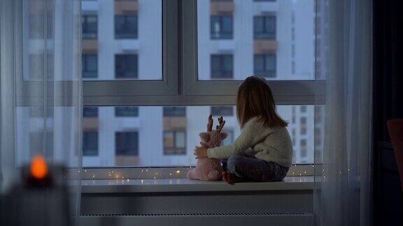 冬天的傍晚女孩坐在窗台上看着窗外飘落的雪花