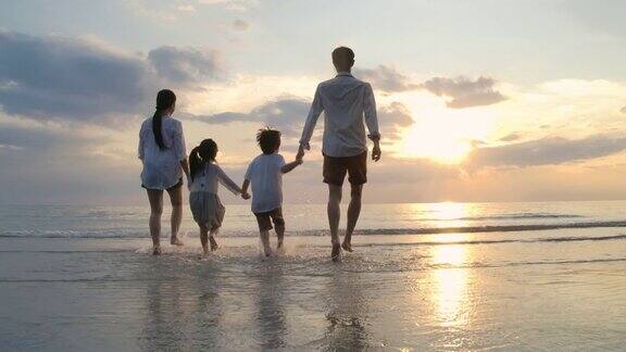 快乐的亚洲家庭在日落的海滩上跑步