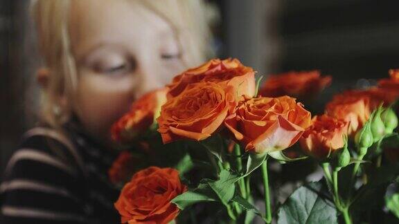 可爱的女孩闻着美丽的橙色玫瑰