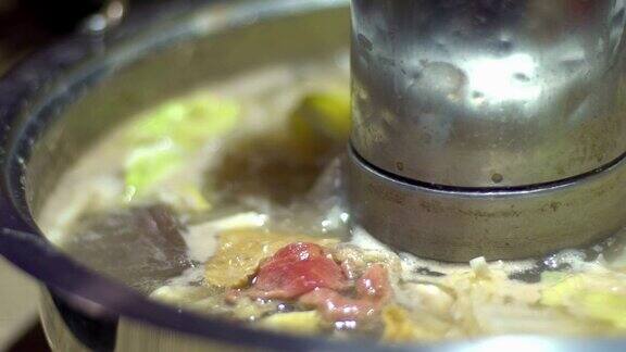 慢动作的火锅与一个甜甜圈形状的黄铜锅在中国切肉