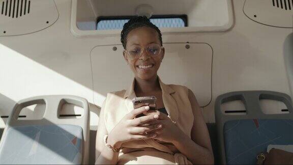 一个年轻女商人在乘坐公交车时使用智能手机的4k视频片段