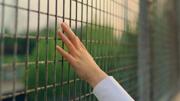 女人用手触摸铁栅栏