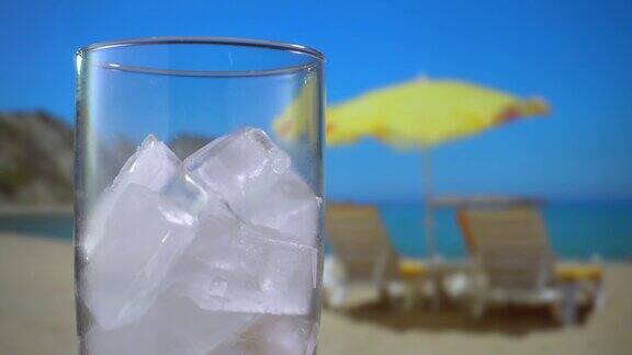 在一个阳光明媚的日子在海滩上放满冰块的玻璃杯