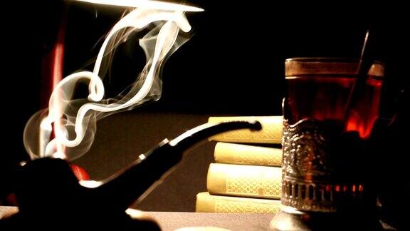 桌子上放着烟斗旁边是一杯茶和一堆书