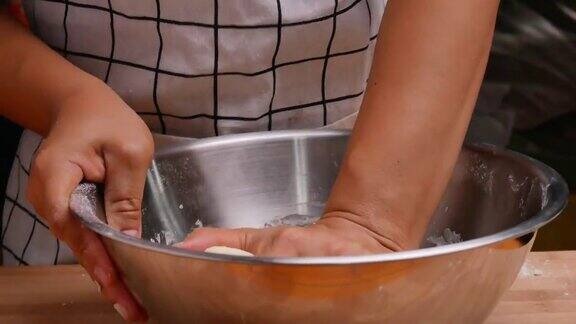 女手揉面团在一个不锈钢容器准备面团自制披萨烹饪过程