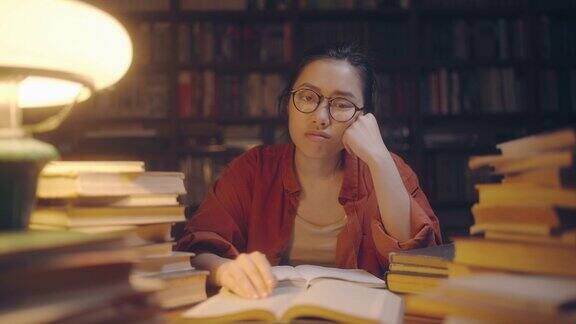 悲伤的亚洲女学生肖像在图书馆学习到很晚疲惫的自由职业者