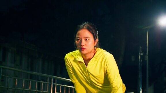 年轻的亚洲女子跑步者休息在激烈的跑步运动后在城市晚上