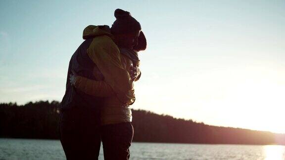 一对情侣在湖边码头上拥抱浪漫的日落