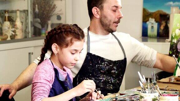 快乐的父亲在给他可爱的小女儿拍照而她正在画画