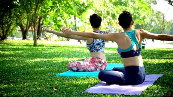 4K年轻女人和教练在公园做瑜伽运动
