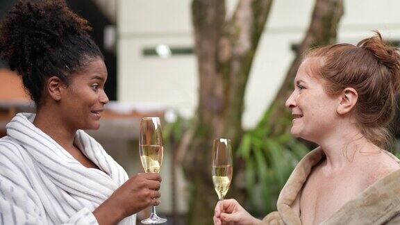 快乐的女人穿着浴袍在水疗中心用香槟祝酒