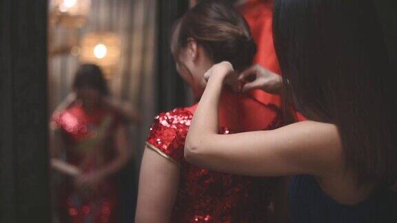 在传统精品店一名亚洲华人女子在姐姐的帮助下对着镜子试穿中国传统旗袍