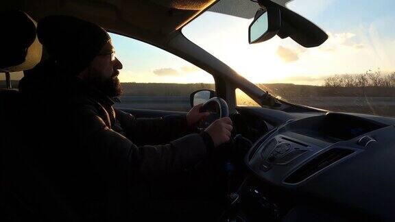 司机一个英俊的年轻人开着一辆车车上装有GoPro相机拍摄在日落时分开车