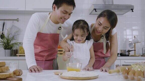 亚洲家庭父亲和母亲教他们的女儿学习做面包女儿玩面团玩得很开心