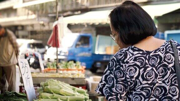 购买水果和蔬菜的资深亚洲妇女站在农贸市场