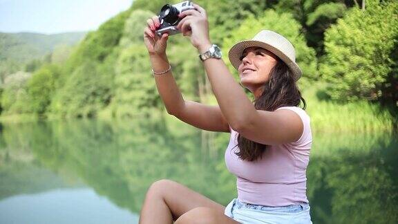 一个年轻美丽的女人放松地坐在一个大坝的边缘拍摄一个美丽的自然湖泊和周围的环境