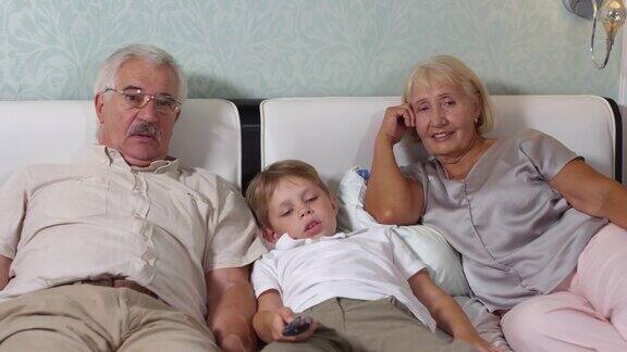 老夫妇和孙子躺在床上看电视