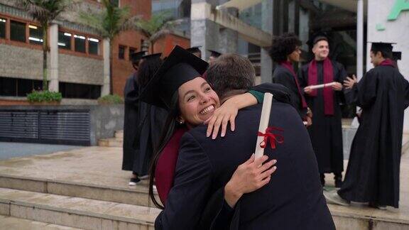 毕业典礼后美丽的年轻女子奔向她的父亲拥抱他