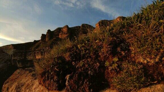 山顶上的夕阳覆岩黑暗的关键日落光在山的视差岩石岩草