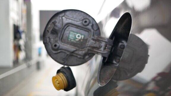 汽车在加油站加油在加油站男性员工用加油喷嘴控制加油泵向汽车中添加汽油