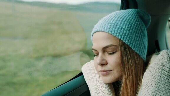 头上戴着冬帽的女人睡在汽车后座上