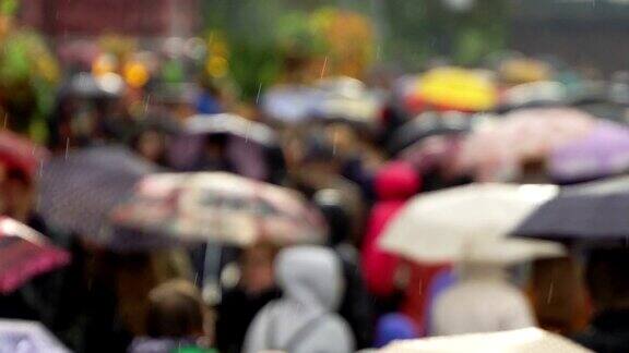 人们在繁忙的商业街撑着雨伞挡雨真正的时间人们在雨中带着雨伞上下班模糊的散景雨天的城市街道的自然背景