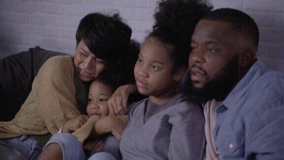 一个混血儿家庭一起坐在公寓的沙发上看电视