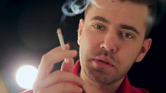 年轻男子在演播室吸烟上瘾问题黑色背景特写