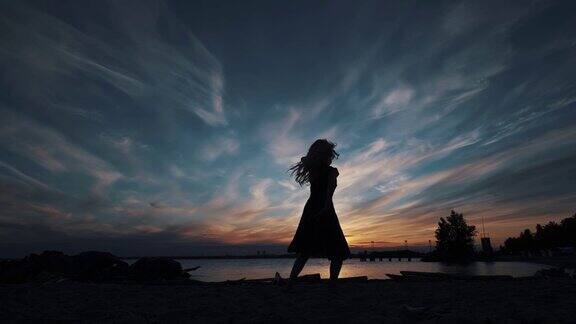 一个女孩的剪影在夕阳下的天空中跳舞