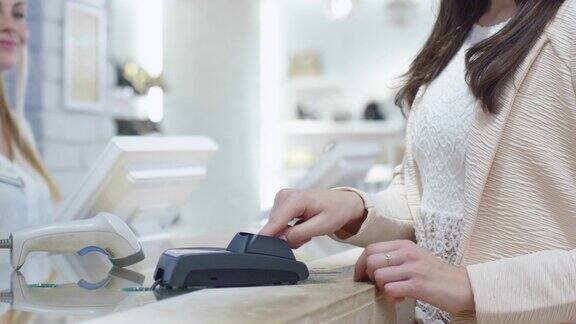 一个年轻的女人在一个百货公司的收银台用信用卡付款的特写镜头