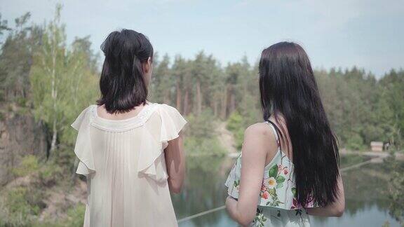 肖像两个可爱迷人的年轻女子穿着夏装看着惊人的自然景色