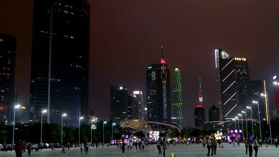 人们在广州的广场上散步大城市晚上高楼大厦用彩色照明