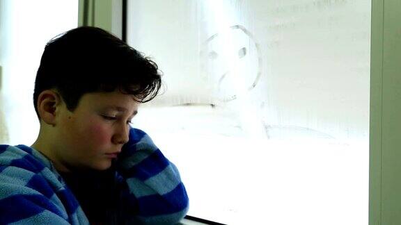 悲伤的孩子在窗户上画着悲伤的脸