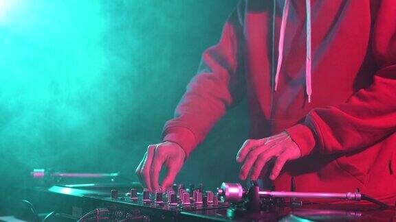 夜店DJ在嘻哈派对上混音黑胶唱片年轻酷炫的音乐节目主持人在烟雾和绿色舞台灯光下表演