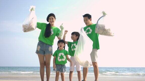 一群志愿者穿着绿色t恤用装满垃圾的塑料袋清理海滩缓慢的运动生态安全概念4k决议