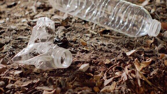 近距离-塑料瓶扔在旁边的另一个瓶子留在土壤上环境问题土壤污染和垃圾填埋