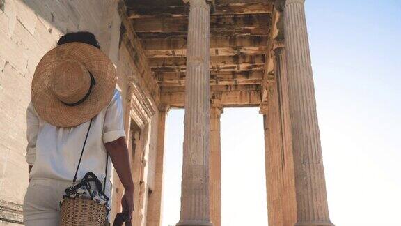 希腊雅典卫城帕台农神庙的年轻女子大帽子时尚白裙太阳镜老式相机