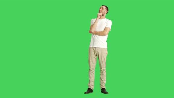 一个随意的男人环顾四周逗乐并做触碰下巴思考手势的长镜头拍摄在一个绿色屏幕背景