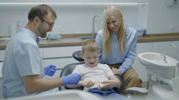 儿科牙医在假颌模型上向孩子和他的母亲讲解如何正确刷牙慢动作