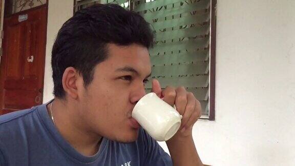 一个亚洲男人用白色的杯子喝咖啡