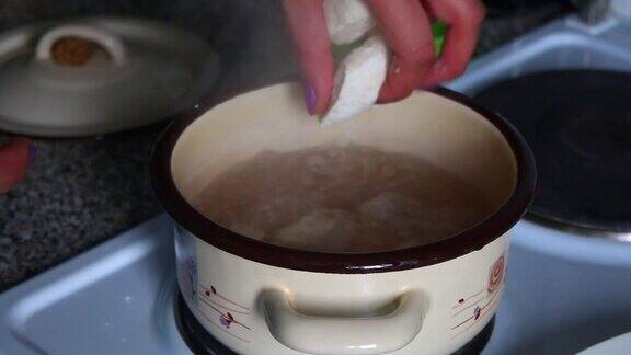 一个女人把懒懒的饺子放在沸水里