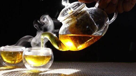 慢镜头热腾腾的菊花茶从一个玻璃罐里倒进一杯热气腾腾的白烟