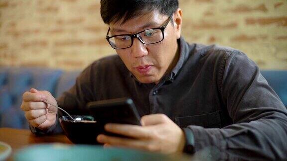 亚洲男人一边吃早餐一边看手机