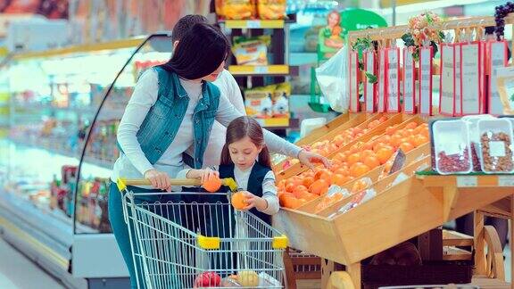 母亲父亲和孩子们在超市里收集包装好的橘子