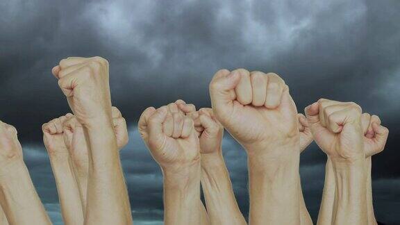 人群举起拳头在灰暗的天空中举起