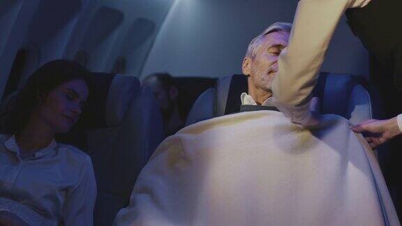 商务人士在私人飞机上睡觉与空姐盖被子